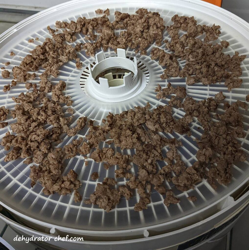 cooked ground beef on the dehydrator tray | dehydrating ground beef | dehydrated ground beef | best foods to dehydrate for long term storage | dehydrating food for long term storage | dehydrated food recipes for long term storage | dehydrating meals for long term storage | food dehydrator for long term storage