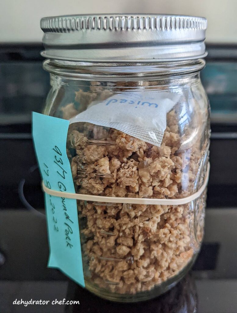 dehydrated ground pork in a clear mason jar with a desiccant packet for moisture control
