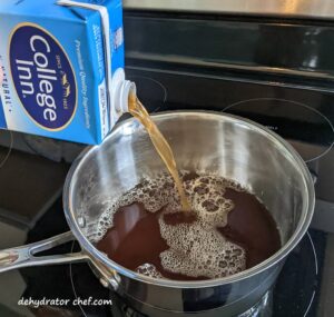 pouring beef stock into a sauce pan so we can make a gelatin for our dehydrated beef stock project