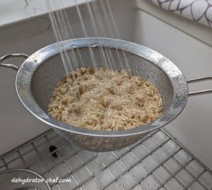 rinsing brown rice with water in a mesh strainer