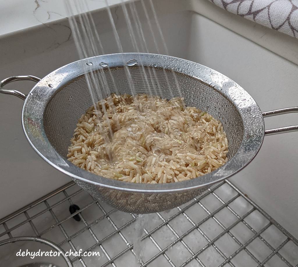 rinsing brown rice with water in a mesh strainer