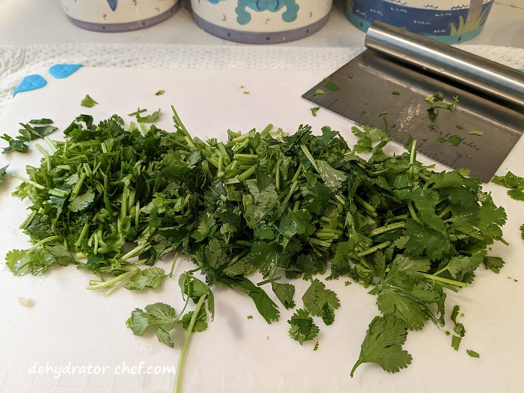 chopped cilantro on a cutting board | dehydrating cilantro | how to dehydrate cilantro | best foods to dehydrate for long term storage | dehydrating food for long term storage | dehydrated food recipes for long term storage | dehydrating meals for long term storage | food dehydrator for long term storage