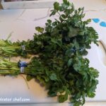 two bunches of cilantro on a cutting board | dehydrating cilantro | how to dehydrate cilantro | best foods to dehydrate for long term storage | dehydrating food for long term storage | dehydrated food recipes for long term storage | dehydrating meals for long term storage | food dehydrator for long term storage