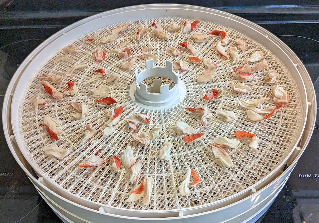 dehydrated imitation crab meat on a dehydrator tray | dehydrated imitation crab meat | dehydrating imitation crab meat | how to dehydrate imitation crab meat | best foods to dehydrate for long term storage | dehydrating food for long term storage | dehydrated food recipes for long term storage | dehydrating meals for long term storage | food dehydrator for long term storage | making dehydrated meals for camping | homemade dehydrated meal recipes | make your own dehydrated camping food | homemade dehydrated camping meals | homemade dehydrated backpacking meals