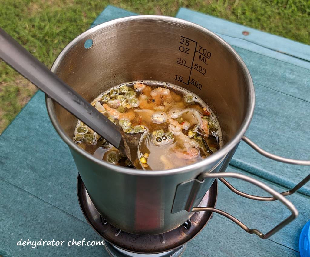 Shown is the seafood curry heating up to a boil on a single-burner camping stove. | Bringing the dehydrated seafood curry mix to a boil on the camp stove. | Dehydrated seafood curry. | Making dehydrated meals for camping. | Homemade dehydrated meal recipes | How to make your own dehydrated camping food. | Homemade dehydrated camping meals. | Homemade dehydrated backpacking meals.