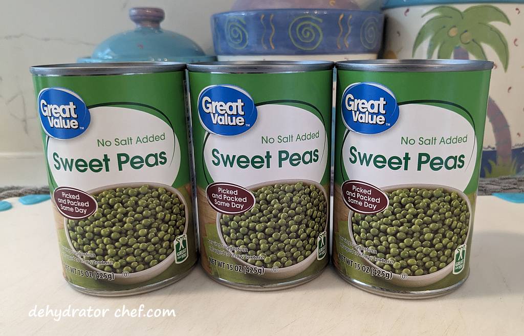 three cans of peas on a cutting board | dehydrating canned peas | dehydrated peas | best foods to dehydrate for long term storage | dehydrating food for long term storage | dehydrated food recipes for long term storage | dehydrating meals for long term storage | food dehydrator for long term storage