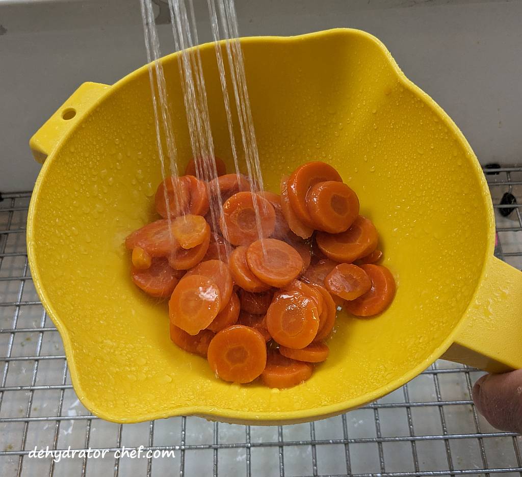 rinsing the sliced carrots under water | dehydrating canned carrots | dehydrated carrots | best foods to dehydrate for long term storage | dehydrating food for long term storage | dehydrated food recipes for long term storage | dehydrating meals for long term storage | food dehydrator for long term storage