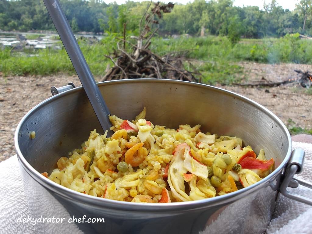 Rehydrated dehydrated seafood curry served for dinner on a canoe camping trip along the river. This lightweight, easy-to-pack homemade dehydrated meal is perfect for outdoor adventures. Customize your dehydrated seafood curry with different spices, vegetables, and seafood options to suit your taste. | Dehydrated seafood curry for canoe camping. | Easy homemade dehydrated camping meals. | How to make dehydrated meals for backpacking. | Lightweight dehydrated food for camping and hiking.