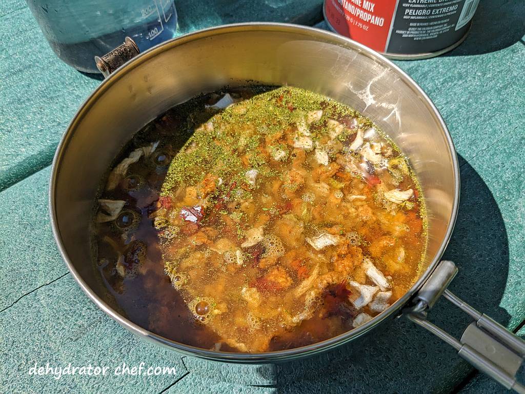 We've added water to the pork tacos and Mexican rice dry mix to start hydrating.  Next, we’ll cover the cooking pot and then let it sit and hydrate for at least five minutes. Be sure to stir it several times so it's well mixed and stays covered and saturated with water.