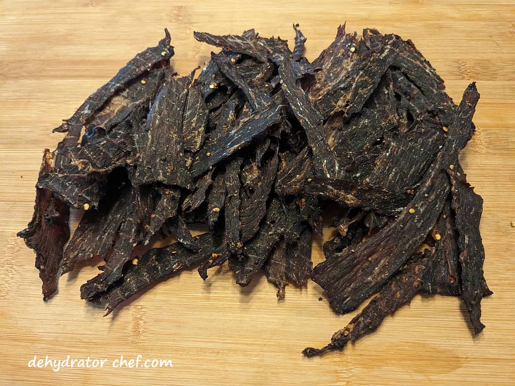 beef jerky on a cutting board | how to make beef jerky | best foods to dehydrate for long term storage | dehydrating food for long term storage | dehydrated food recipes for long term storage | dehydrating meals for long term storage | food dehydrator for long term storage
