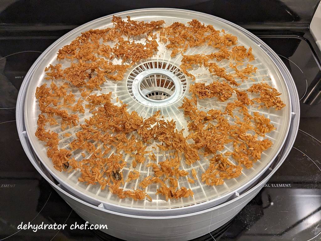 The Zatarain's Jambalaya Rice has finished dehydrating. We're letting it cool down to room temperature for a few minutes. The next step is to transfer the dried rice into canning jars for the equalizing and conditioning phase, which is Step 5.