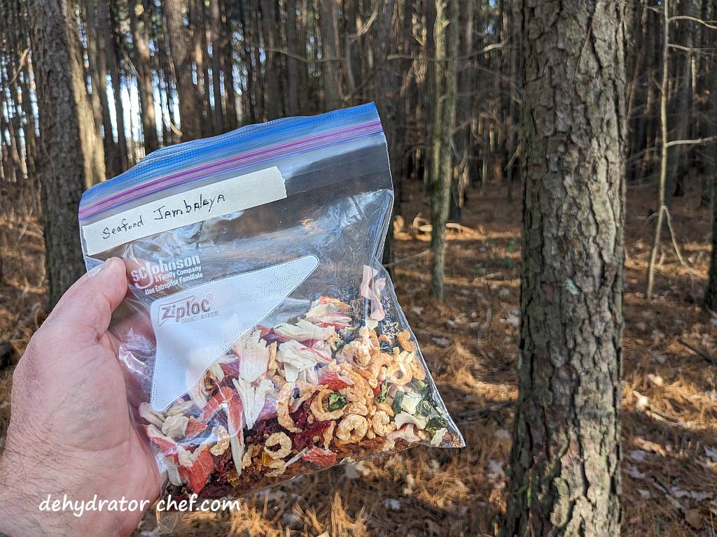 Shown is a bag of dehydrated seafood jambalaya along a trail as we head to the campsite. | Dehydrated seafood jambalaya on the trail. | Dehydrated seafood jambalaya recipe. | Making dehydrated meals for camping. | Homemade dehydrated meal recipes. | Make your own dehydrated camping food. | Homemade dehydrated camping meals. | Homemade dehydrated backpacking meals.