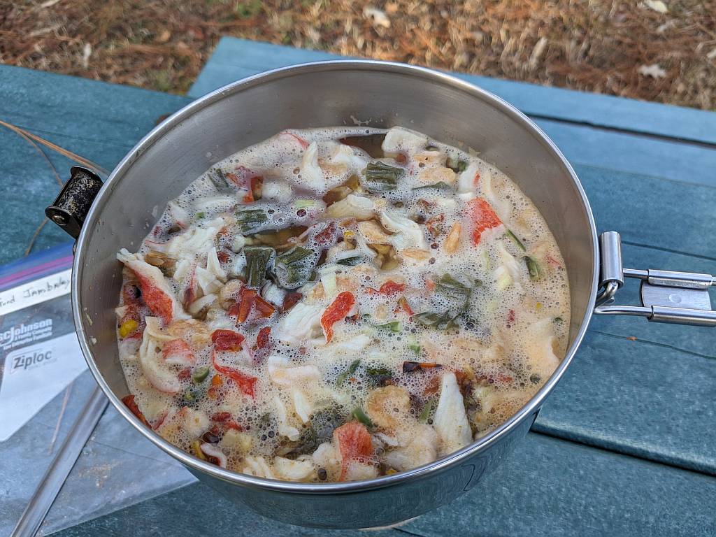 Shown is the seafood jambalaya is coming to a boil in a cooking pot over a single burner camping stove. It's time to turn it down to a simmer. | The seafood jambalaya mix is simmering in the MSR 1.1 liter Alpine Stowaway pot. | Dehydrated seafood jambalaya recipe. | The best foods to dehydrate for long term storage. | Dehydrating food for long term storage. | Dehydrated food recipes for long term storage. | Dehydrating meals for long term storage. | Using a food dehydrator for long term storage.