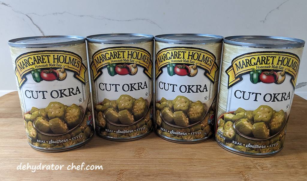 four cans of cut okra on a cutting board | dehydrated okra | dehydrating okra | how to dehydrate okra | best foods to dehydrate for long term storage | dehydrating food for long term storage | dehydrated food recipes for long term storage | dehydrating meals for long term storage | food dehydrator for long term storage
