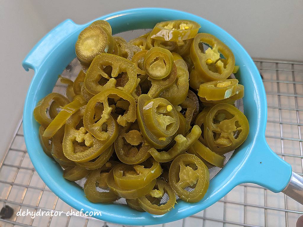 draining jarred jalapeno peppers through a strainer so we can dehydrate them | dehydrating jalapeno peppers | dehydrated jalapeno peppers | drying jalapeno peppers | dehydrated camping food recipes | recipes using dehydrated food | make your own dehydrated meals | homemade dehydrated camping meals