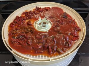 Eleven ounces of processed chipotle peppers in adobo sauce on a dehydrator tray