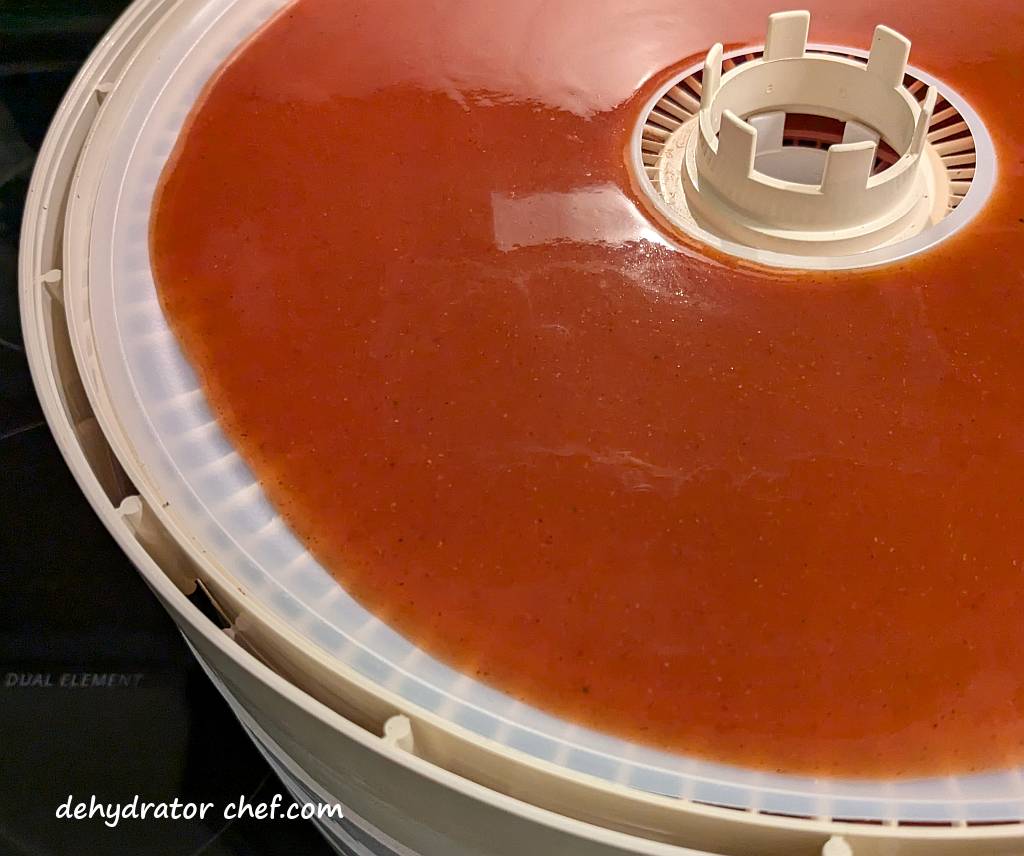 A close-up of the processed enchilada sauce on the fruit roll sheet. The no-spill lip feature of the sheet helps control any spillage as we carry the tray from the workspace to the dehydrator.