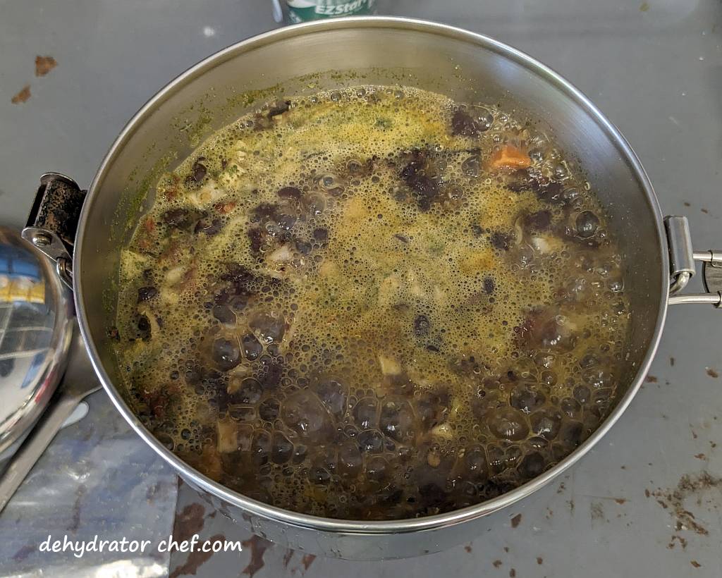 dehydrated sweet potato black bean quinoa bowl ingredients simmering on the backpacking stove for two minutes