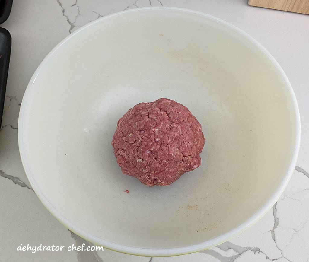 a large ground beef and breadcrumb meatball in a mixing bowl