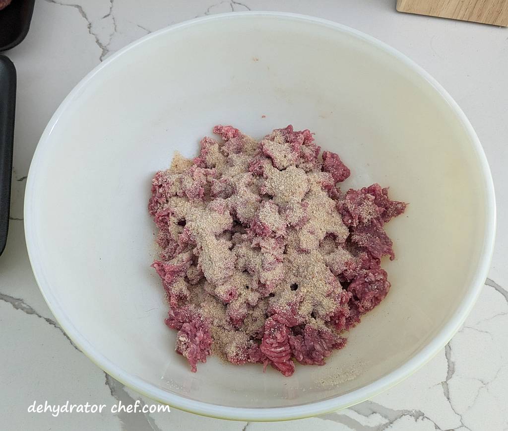 layering in breadcrumbs and ground beef into a mixing bowl that we will form into a meatball