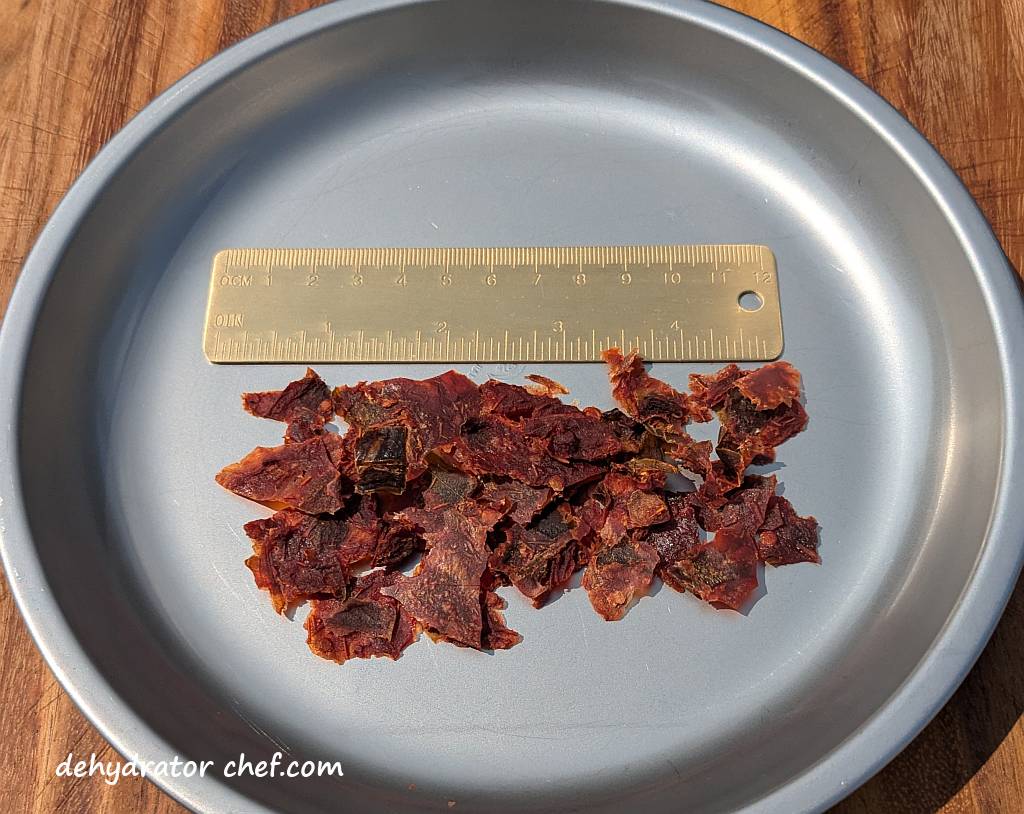 Shown above are eight grams of dehydrated salsa flakes. We'll break up the larger flakes into smaller pieces as we build out our homemade dehydrated camping meals.  Smaller salsa flakes will reconstitute much faster.