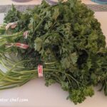 Several bunches of fresh parsley on a cutting board that we will dehydrate for long term storage.