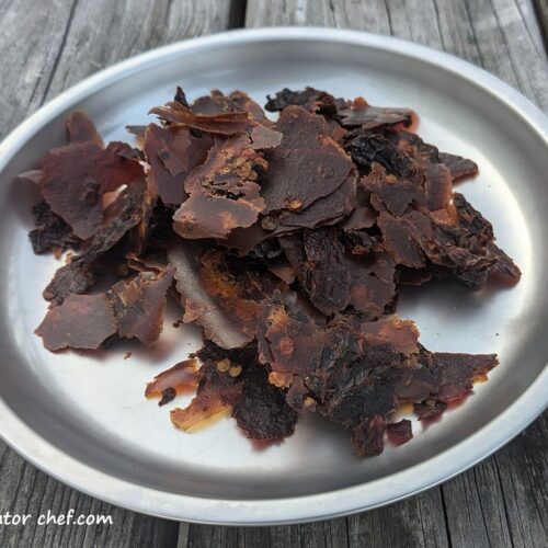 Dehydrated Rotel diced tomatoes with green chilies on a plate, ready for long-term storage and use in homemade backpacking meals.