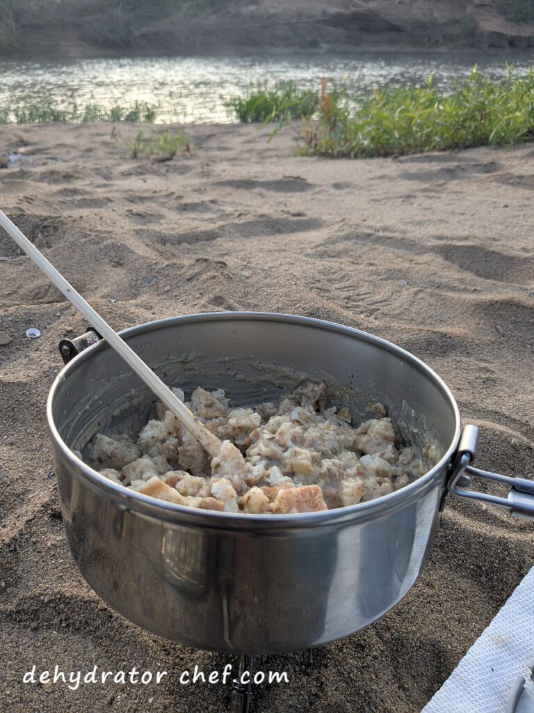 Enjoying a breakfast of dehydrated biscuits and gravy on a sand and gravel river bank.